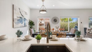 A modern kitchen with a central island, a dining area with outdoor views, and a large abstract painting on the wall. - The Vues 6|Resort Pool, Ping Pong Table, Private Blacony (St. George)
