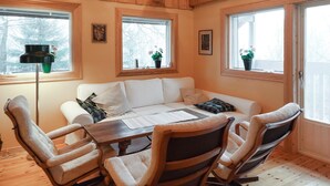 A cozy room with a white sofa, a wooden dining table, and chairs. There are windows with plants on the windowsills. - 2 bedroom lovely home in Klippan (Klippan)