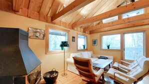 A cozy cabin interior with a wooden ceiling, a fireplace, a sofa, a dining table with chairs, and large windows offering views of the outdoors. - 2 bedroom lovely home in Klippan (Klippan)