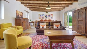 A living room with a wooden ceiling, a sofa with fox-themed pillows, a yellow armchair, and a coffee table. - Gîte De L’Egal – Cadouin, Sleeps 10, Air-Conditioned, Private Pool, Périgord Charm (Le Buisson-de-Cadouin)