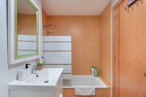 Un baño con lavamanos, espejo y ducha blancos.