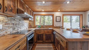 Una cocina con armarios de madera, salpicadero de piedra y un amplio ventanal.