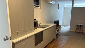 A modern kitchen with built-in appliances, a microwave, and a sink. - Studio Apartment 100 meters from lake and walking track  (Cromwell)