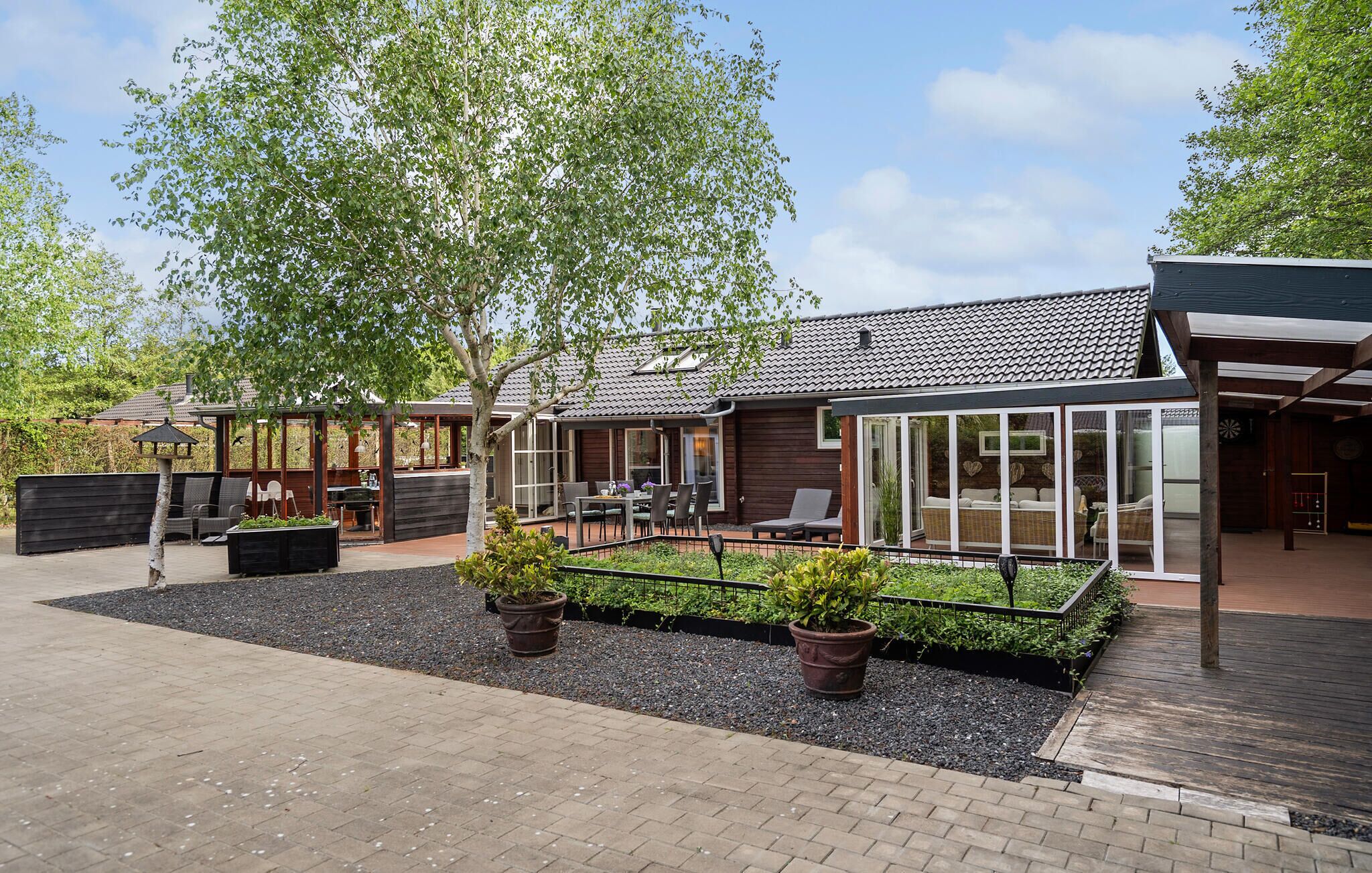 A modern house with a patio area, outdoor seating, and a garden.