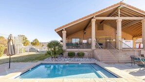 A swimming pool with a covered patio area, a fenced yard, and a clear sky. - Labor Day Getaway | Pool, Spa & Pickleball (St. George)
