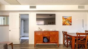 A dining area with a wooden table and chairs, a wooden cabinet, and a painting on the wall.