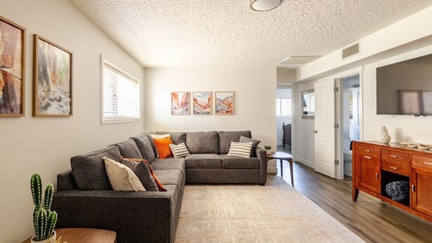 A spacious living area with a large sectional sofa, a wooden coffee table, and a cactus plant. - Labor Day Getaway | Pool, Spa & Pickleball (St. George)