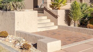 A stucco building with a tiled roof, a covered porch, and a set of stairs leading to a door. - Labor Day Getaway | Pool, Spa & Pickleball (St. George)