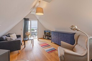 Un loft moderno con comedor, un sofá, una silla, un televisor y una estantería.