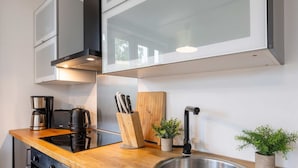 A modern kitchen with a wooden countertop, stainless steel sink, and a coffee maker.