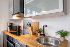 Una cocina moderna con encimera de madera, pileta de acero inoxidable y cafetera.