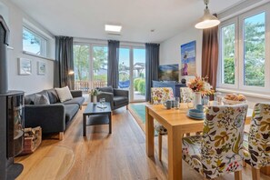 Una sala de estar moderna con sofá, mesa de centro y zona de comedor con sillas estampadas.