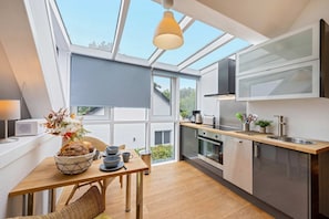 Une cuisine moderne dotée d’une verrière, d’une table à manger en bois et offrant une vue sur l’extérieur.