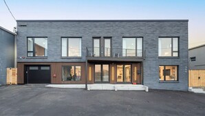 Un moderno edificio de dos pisos con techo plano, ventanas amplias y un balcón.