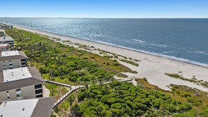 A coastal hotel with a beach view, a walking path, and lush greenery.