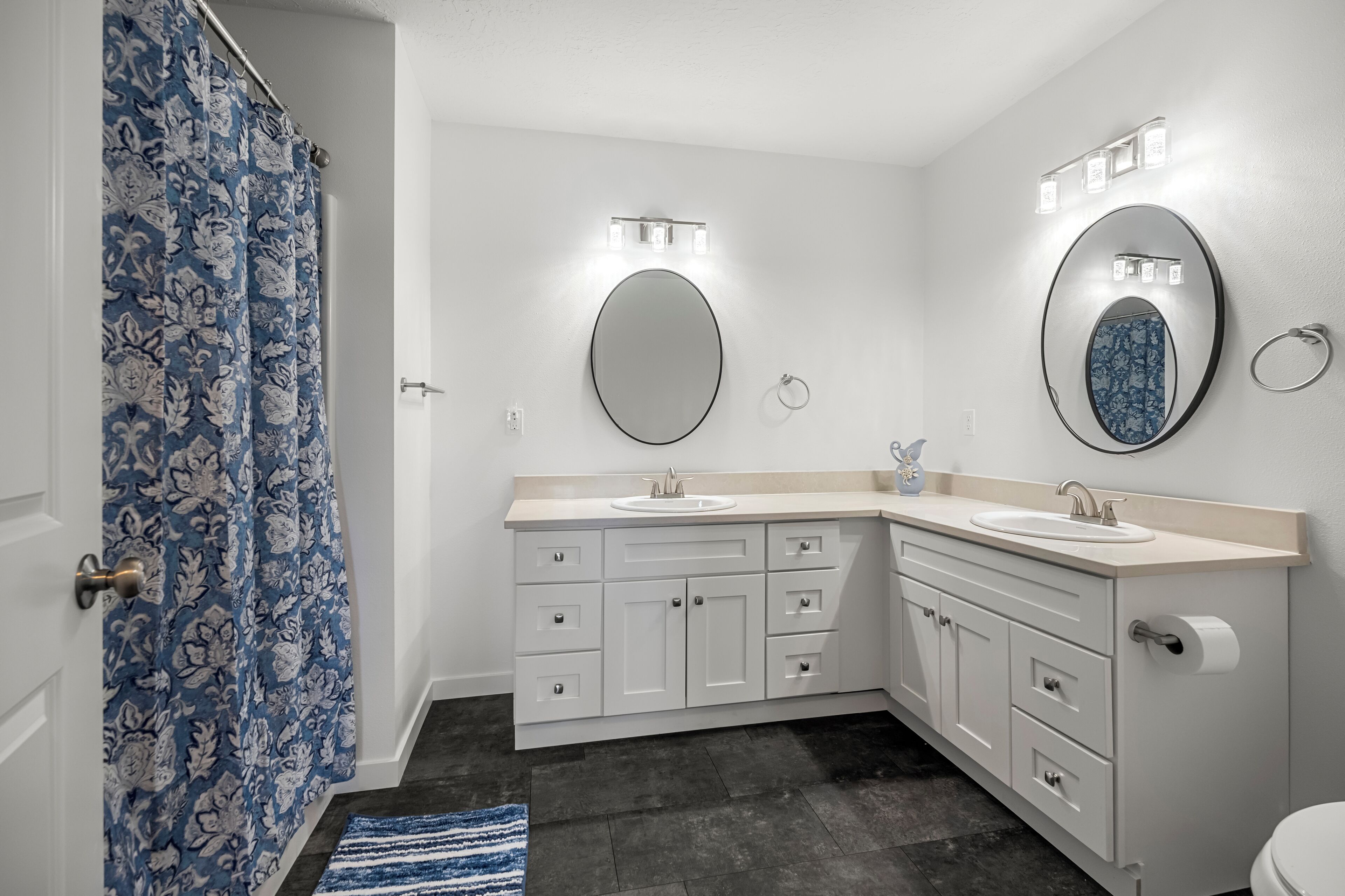 Une salle de bain avec deux lavabos, des toilettes et un rideau de douche.