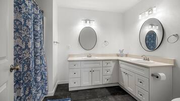 Une salle de bain avec deux lavabos, des toilettes et un rideau de douche.