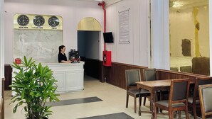 A hotel lobby with a reception desk, seating area, and a large potted plant. - Amy Hotel Hue (Hue)