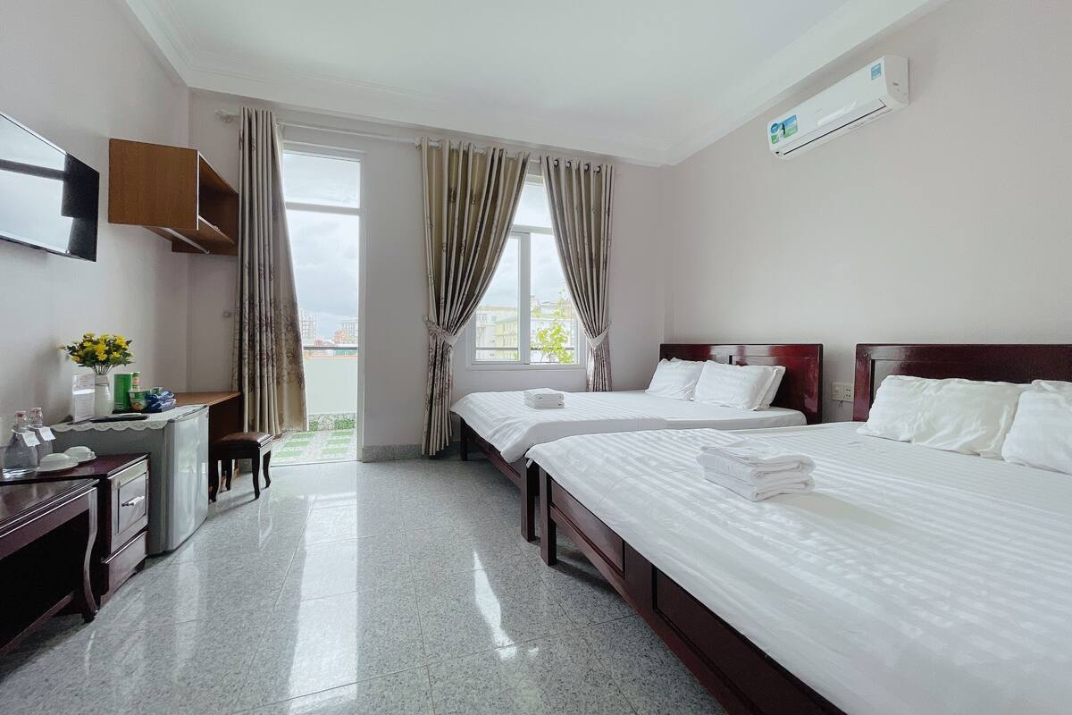 A hotel room with two beds, a desk, and a TV.