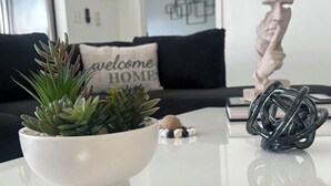 Een moderne woonkamer met een witte salontafel, een vetplant in een pot en een sculptuur.
