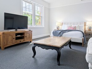 A bedroom with a TV, wooden furniture, a bed with pillows, and a window with a view.