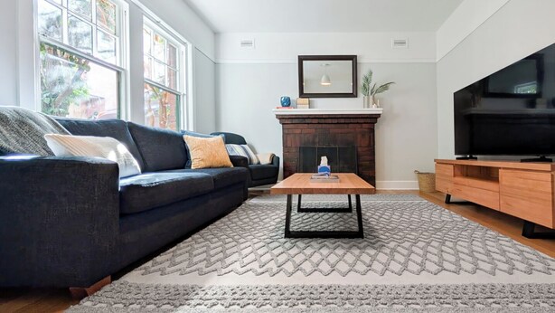 A living room with a dark blue sofa, a wooden coffee table, a fireplace, and a television on a wooden stand.