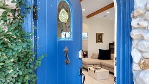 Eine blaue Tür mit Fenster, eine Steinwand und ein Wohnzimmer mit Sofa und Couchtisch.