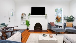 Ein Wohnzimmer mit Kamin, bequemen Sitzmöglichkeiten und einem Flachbildfernseher.