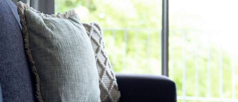 Ein Sofa mit Kissen und Blick ins Grüne.