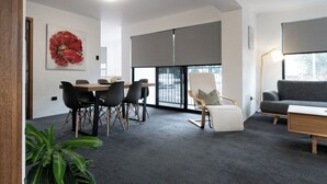 Un espacio de oficina moderno con comedor, un sofá y un amplio ventanal con persianas.