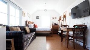 A cozy bedroom with a bed, a sofa, a desk, and a TV.