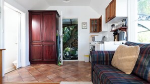 A spacious living area with a large wooden wardrobe, a sofa, and a kitchen area with a coffee machine.