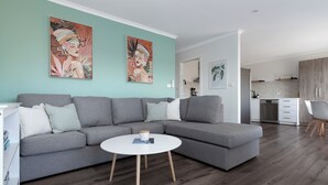 A modern living room with a grey sectional sofa, a round coffee table, and artwork on teal walls. - Cosy & Sweet: Near the City, WiFi & Parking (Launceston City)
