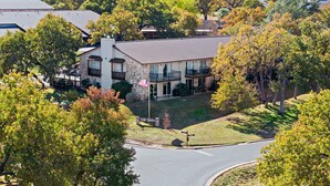 A two-story building with a stone facade, a balcony, and a sign reading "The Oaks."