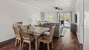 A dining area with a wooden table and chairs, a sofa, and a ceiling fan.