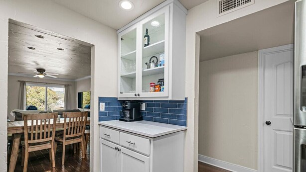 A kitchen with white cabinets, a coffee maker, and a tiled backsplash.