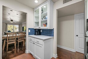 A kitchen with white cabinets, a coffee maker, and a tiled backsplash. - Cozy Condo in Horseshoe Bay (Horseshoe Bay)