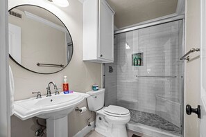 Ein Badezimmer mit Waschbecken, Spiegel, Toilette und einer Duschkabine.