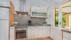 A compact kitchen with a built-in oven, a coffee maker, and a window providing a view of the outdoors. - Villa La Sort 140 - By Dream Villas Pollensa (Pollensa)