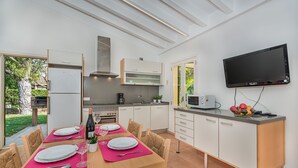 A modern kitchen with a dining area, equipped with a flat-screen TV, a microwave, and a sink. - Villa La Sort 140 - By Dream Villas Pollensa (Pollensa)