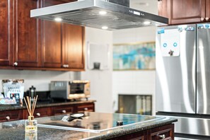 Une cuisine avec des meubles en bois, un réfrigérateur en acier inoxydable, un four à micro-ondes et une machine à café.