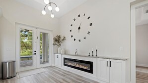 A modern kitchen with a built-in fireplace, white cabinetry, and a large wall clock. - Tropical Paradise in North Port! (North Port)