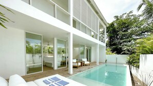 A modern house with a swimming pool, wooden deck, and outdoor seating area. - Sunset Bungalow (Canggu)