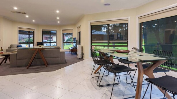 A spacious living area with a dining table and chairs, a sofa, and a television. - Relaxing 3bd in tranquil setting (Kennington)