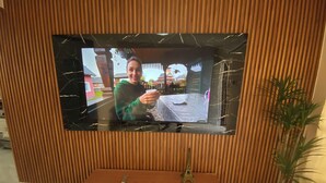 Un televisor montado en una pared de madera con acabado similar al mármol.