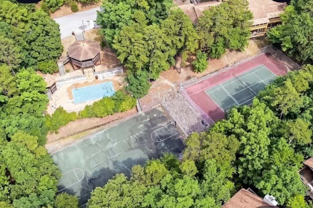 Vista aérea de una propiedad con piscina, canchas de tenis y un pabellón.