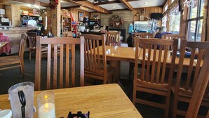 Un restaurante con interiores de madera, mesas, sillas y una barra con diversos artículos.