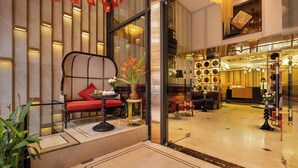 A lobby with a seating area, a reception desk, and a decorative wall with flags. - Le Premier Hotel & Rooftop Bar (Hanoi)