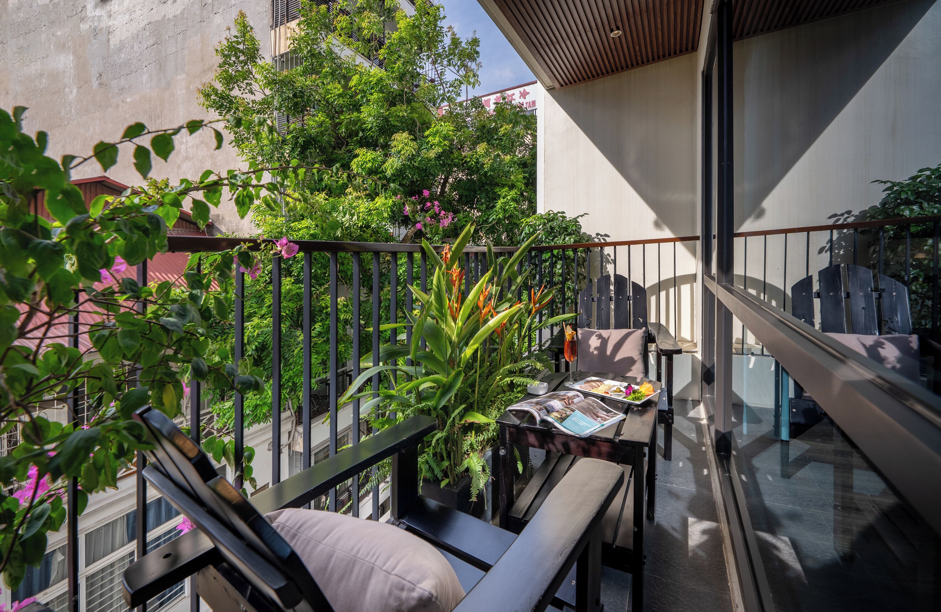 A balcony with a table, chairs, and a potted plant.