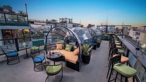 A rooftop terrace with seating areas, including a semi-enclosed space with a transparent roof, surrounded by chairs and tables. - Le Premier Hotel & Rooftop Bar (Hanoi)